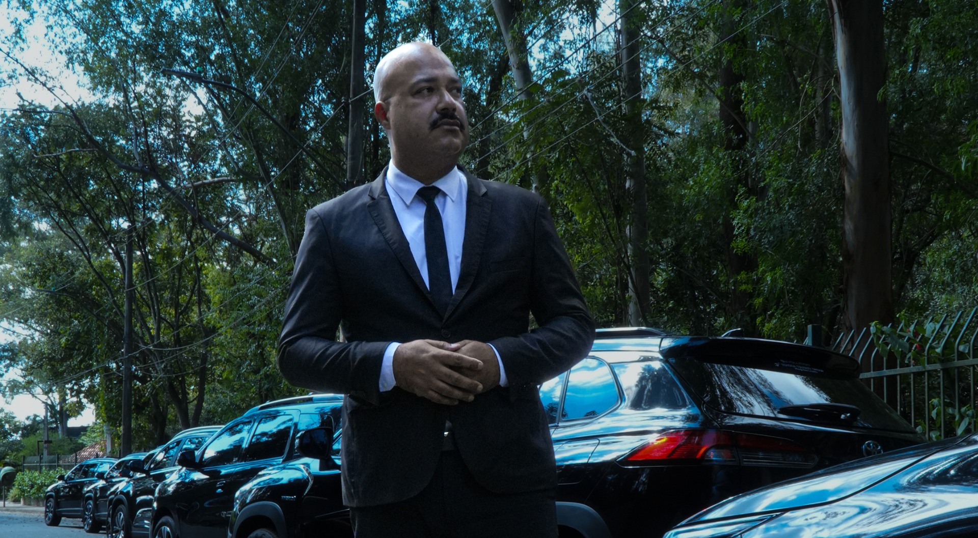 Uniformed executive chauffeur next to a black sedan